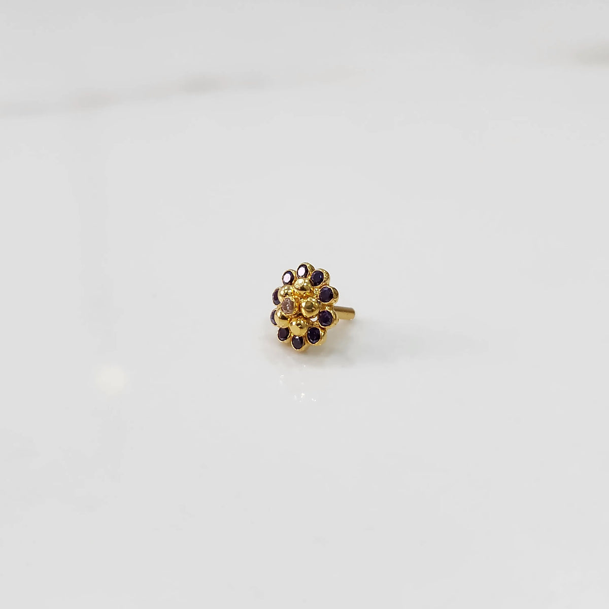 Gold floral ring with purple gemstone petals and textured gold center