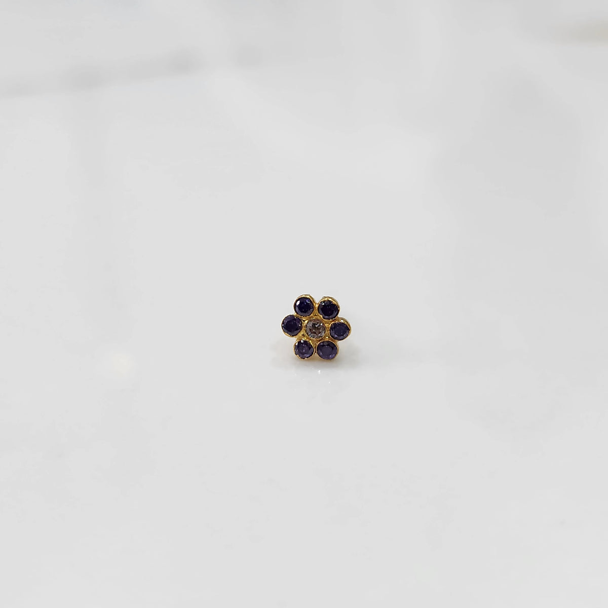 Nose pin design gold with purple stone floral cluster front view on white background