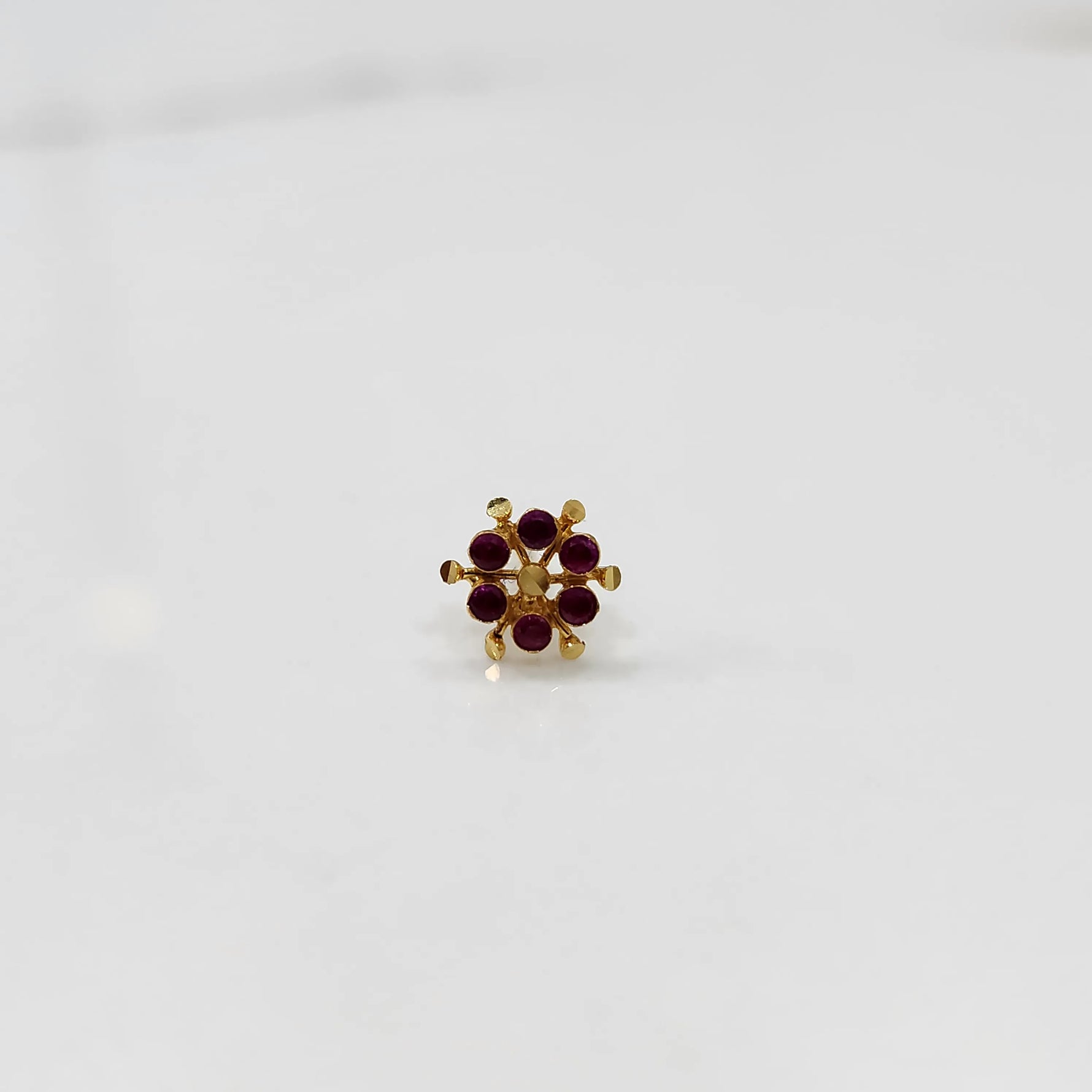 Front view of gold statement ring with red cabochon gemstones in scattered cluster design