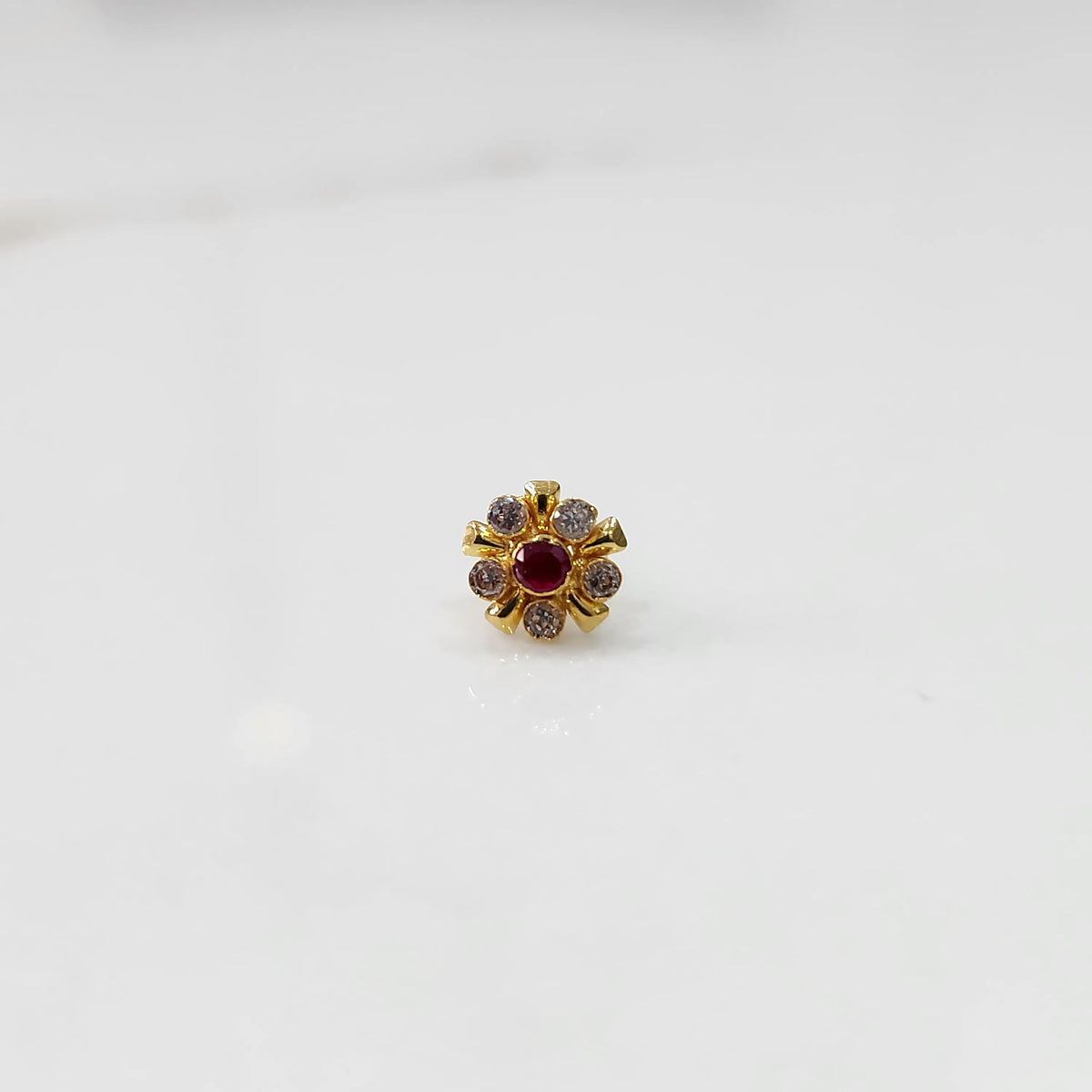 Gold floral nose pin with red center stone, product shot