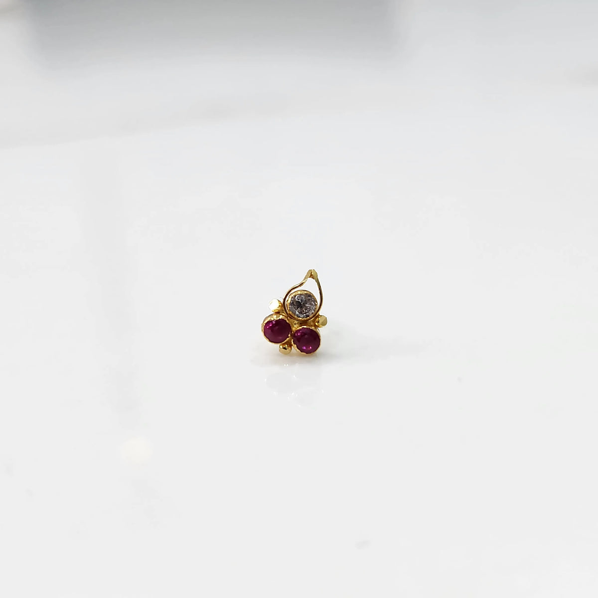 Side view of gold statement ring with red and clear gemstones in cluster design