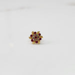 Front view of gold statement ring with red and clear gemstones in leaf-patterned cluster design