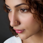 Woman wearing a gold nose pin with red stone accent