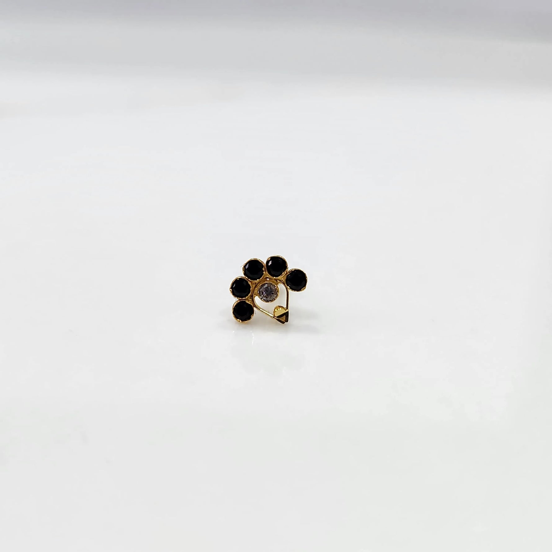 Gold ring with black and clear flower cluster and dangling drop stone