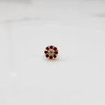 Top view of gold ring with clear center stone and ruby-red petal stones