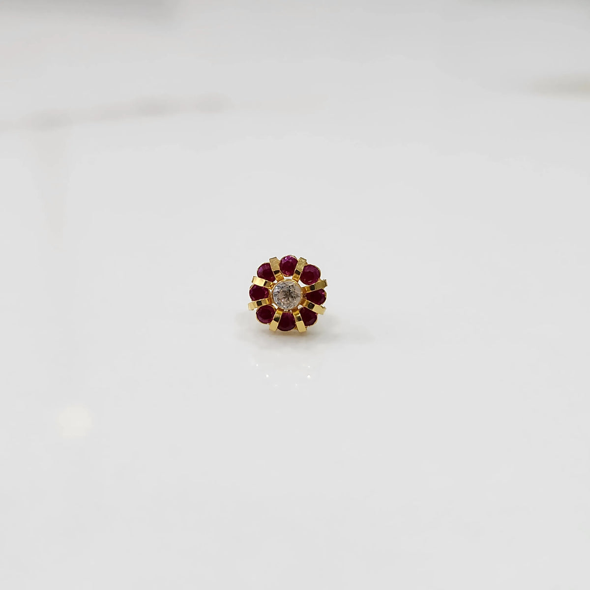 Top view of gold ring with clear center stone and ruby-red petal stones
