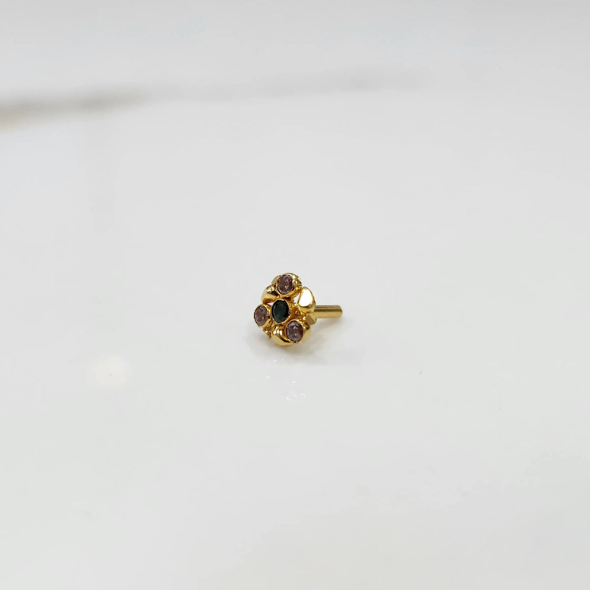 Side view of gold ring featuring green and purple gemstone cluster in round floral pattern