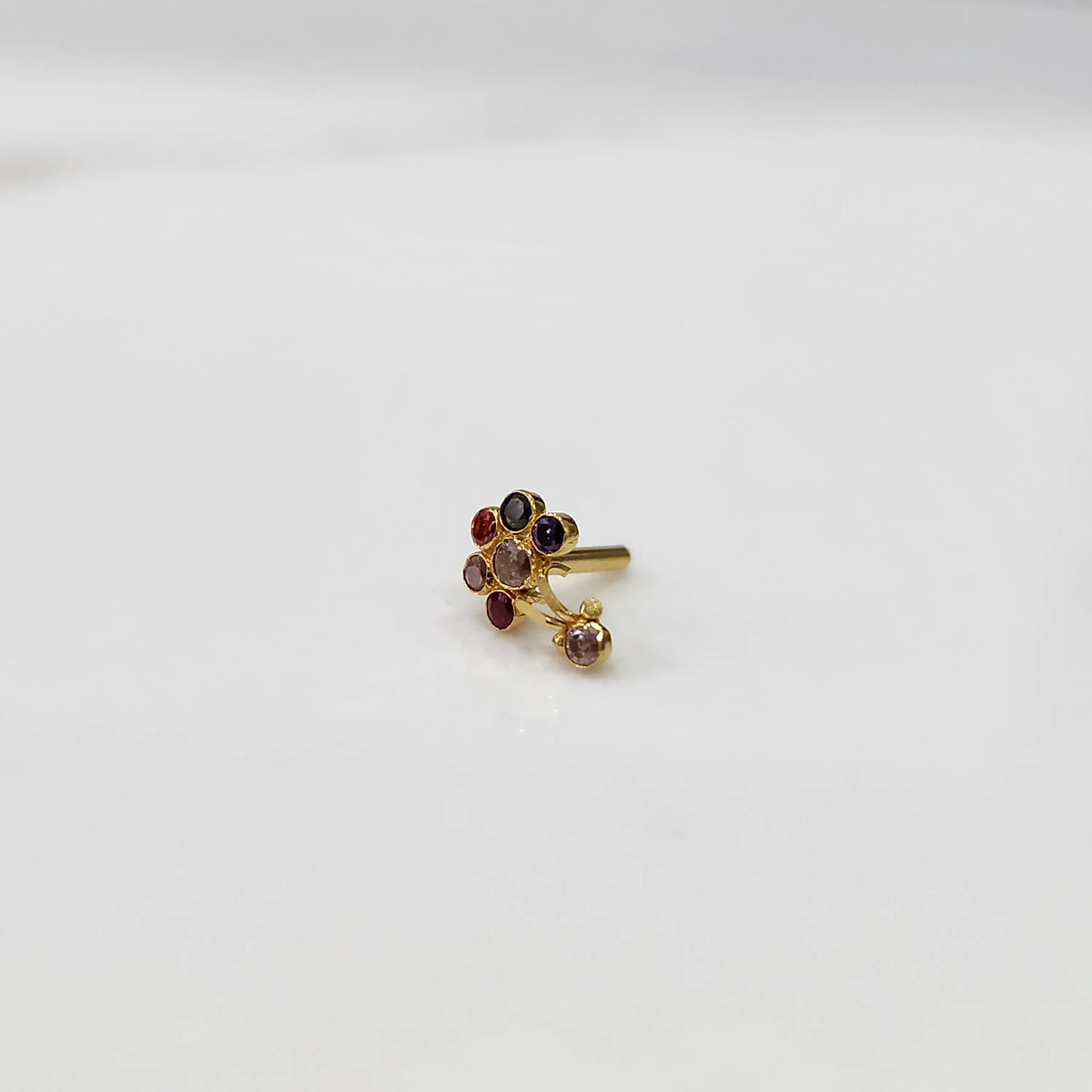 Front view of gold ring featuring floral gemstones with drop pendant detail