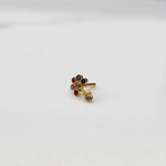 Front view of gold ring featuring floral gemstones with drop pendant detail
