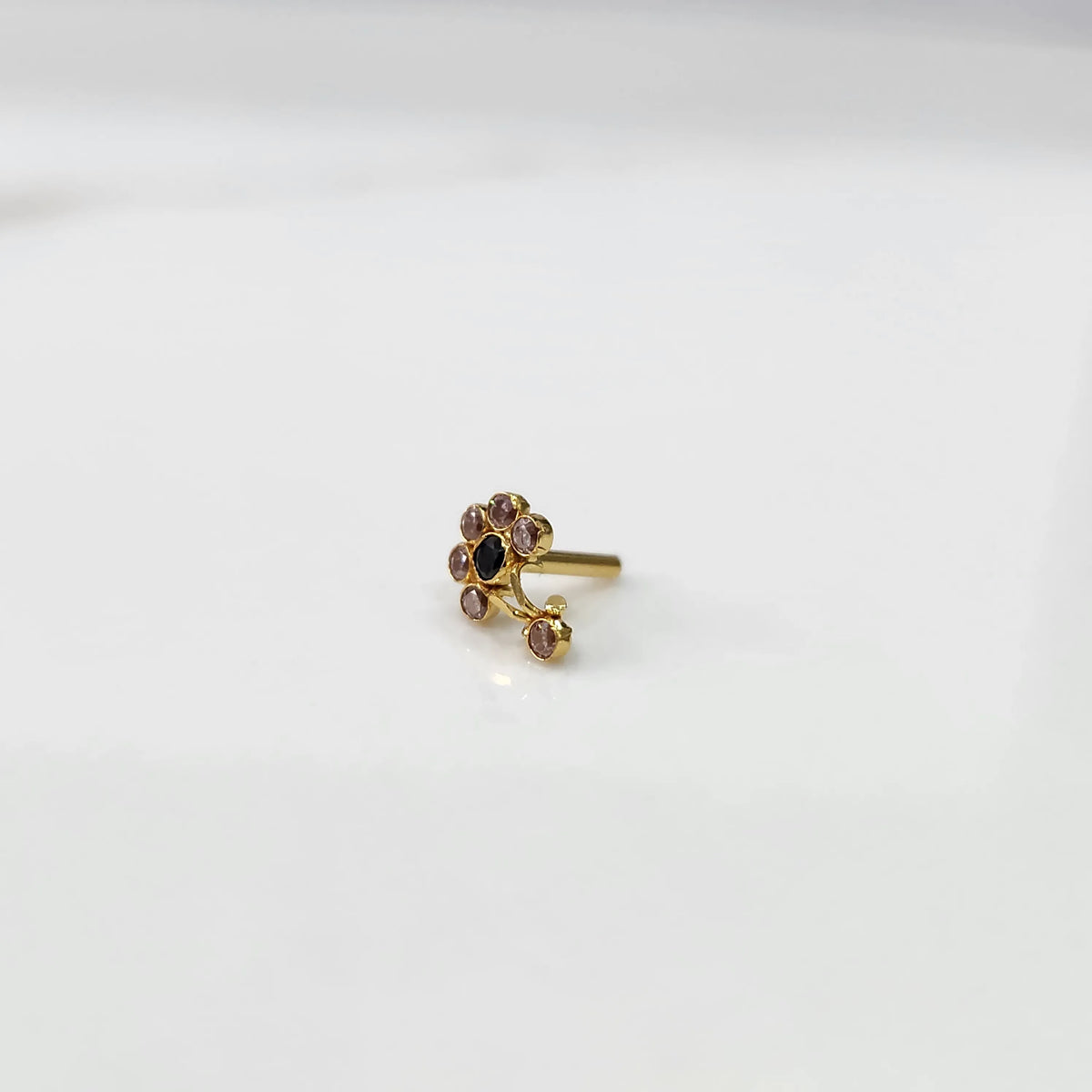 Front view of gold ring featuring purple floral gemstones with black center and drop pendant