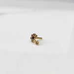 Front view of gold ring featuring purple floral gemstones with black center and drop pendant