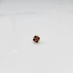 Front view of gold ring featuring red gemstone cluster in round floral pattern