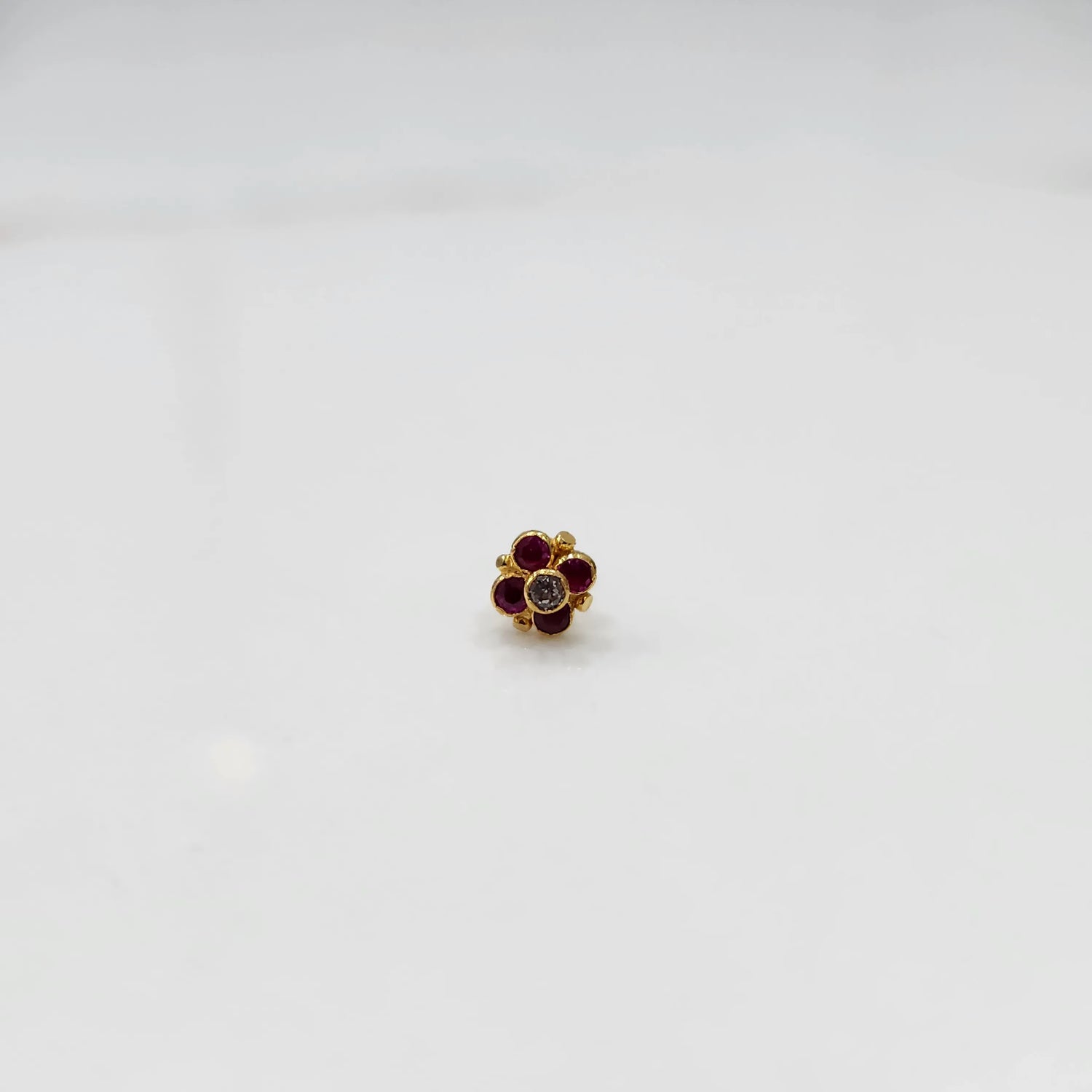 Front view of gold ring featuring red gemstone cluster in round floral pattern