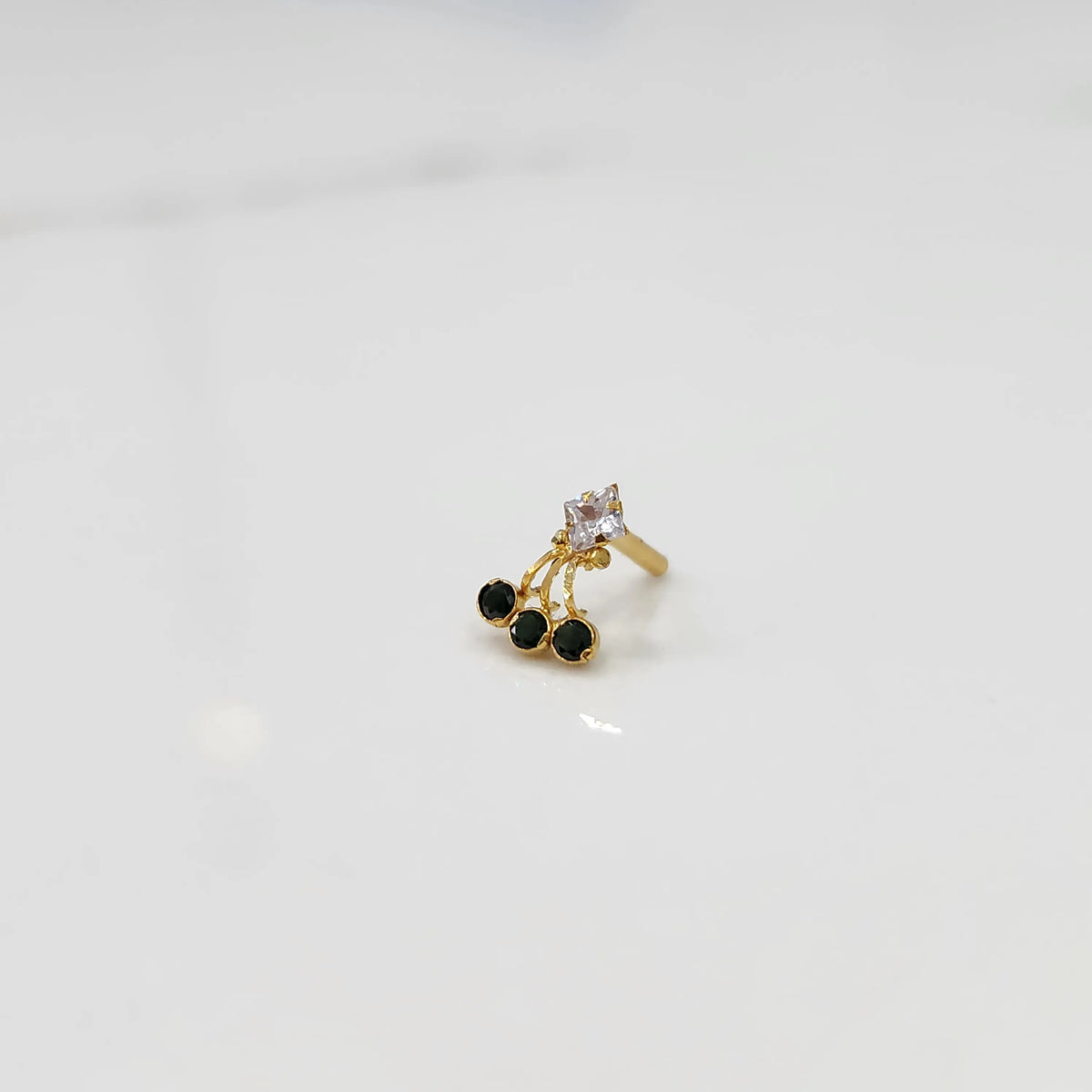 Gold ring with square clear stone and green gemstone drop design