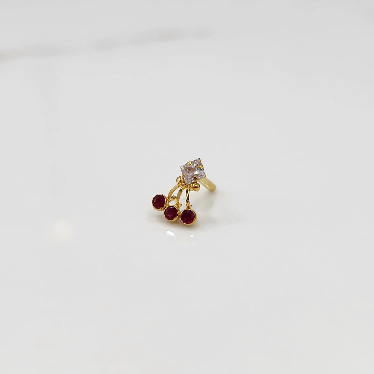 Gold ring with square clear stone and red gemstone drop design