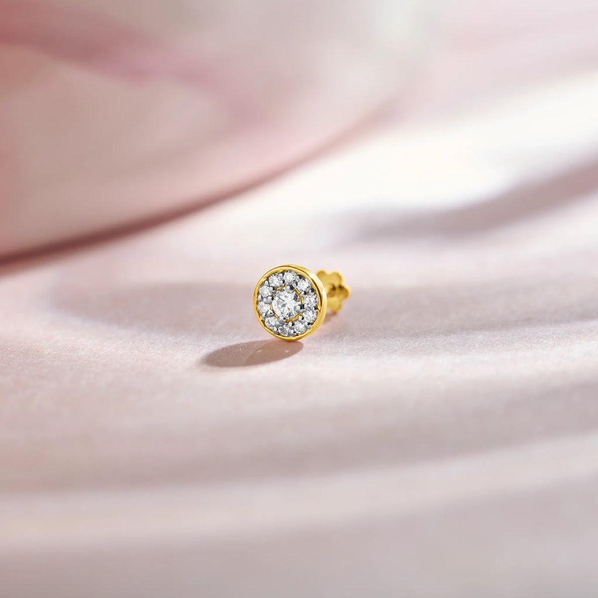 Gold nose stud featuring a round bezel-set gemstone cluster design