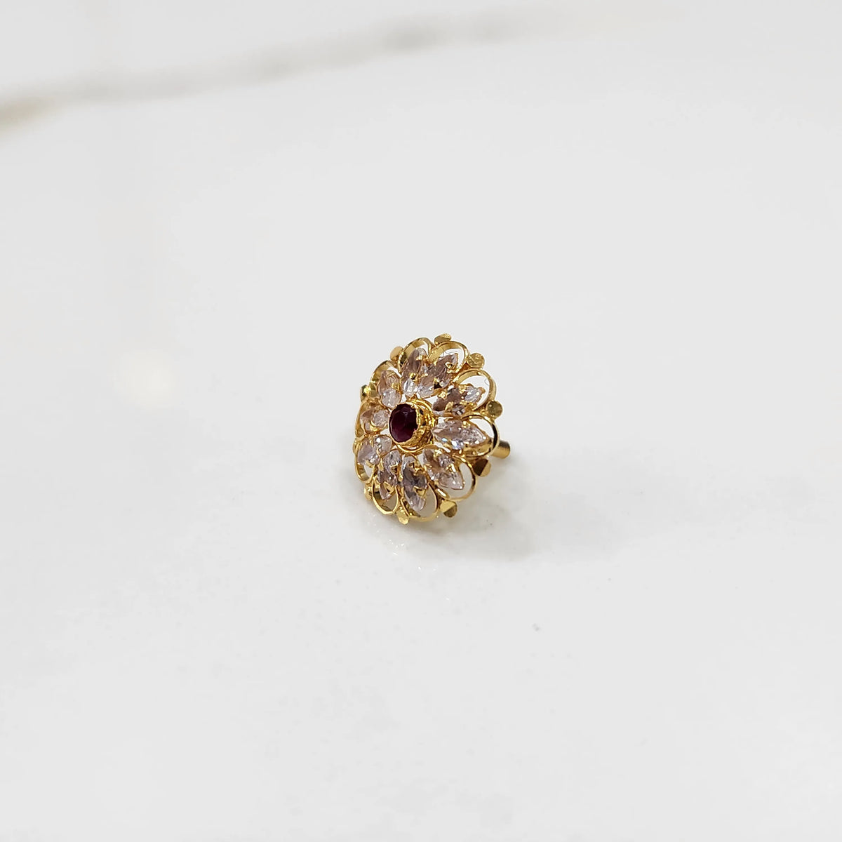 Front view of gold ring with round clear petals and red center stone