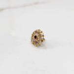 Front view of gold ring with round clear petals and red center stone