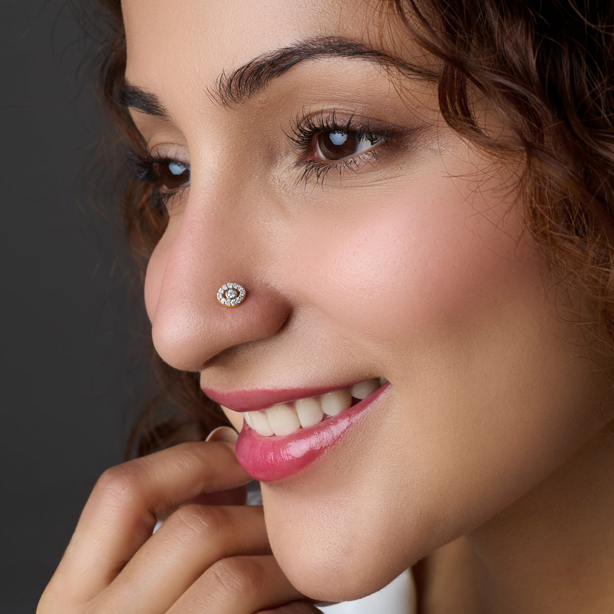 Close-up of circular gold nose stud with stones