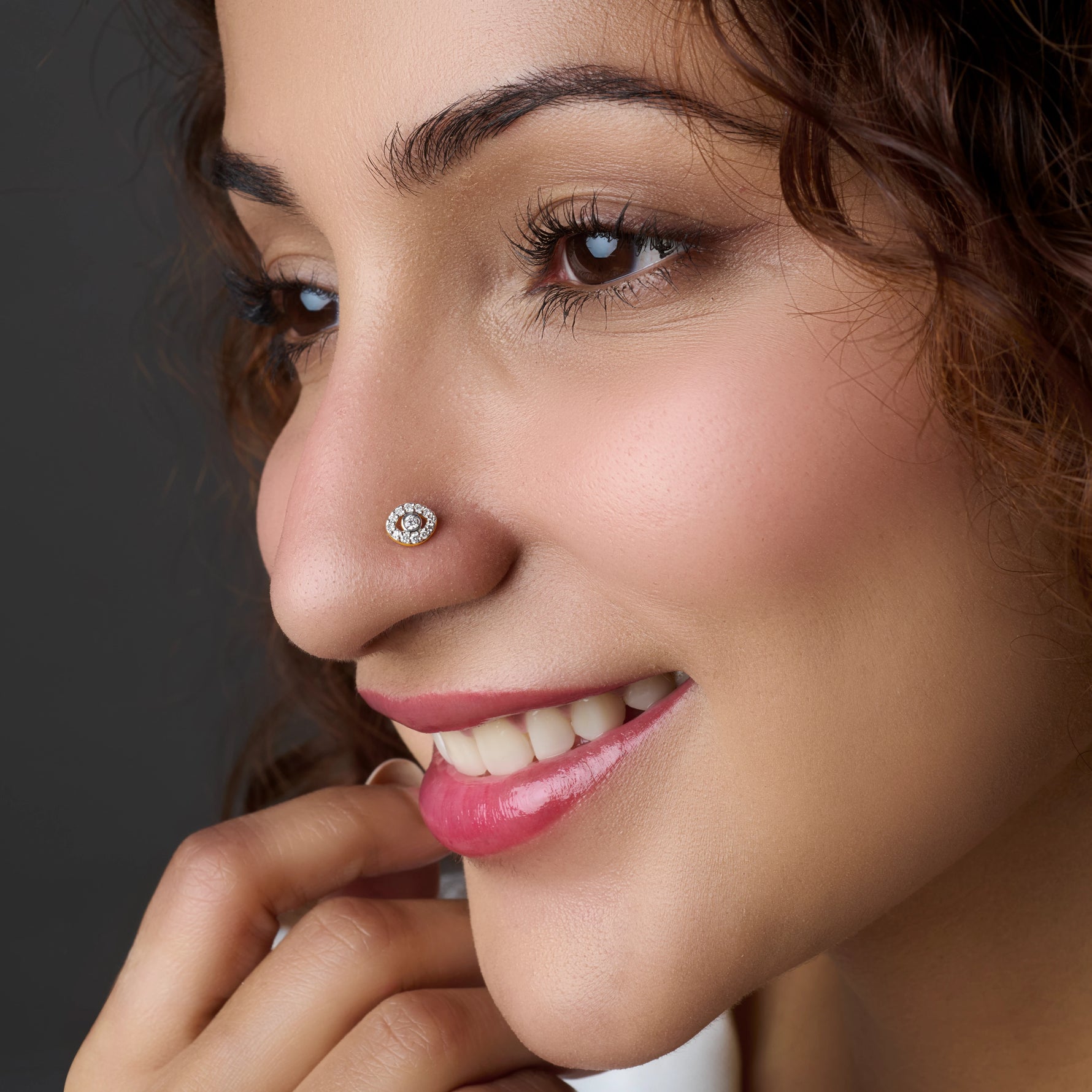 Close-up of circular gold nose stud with stones