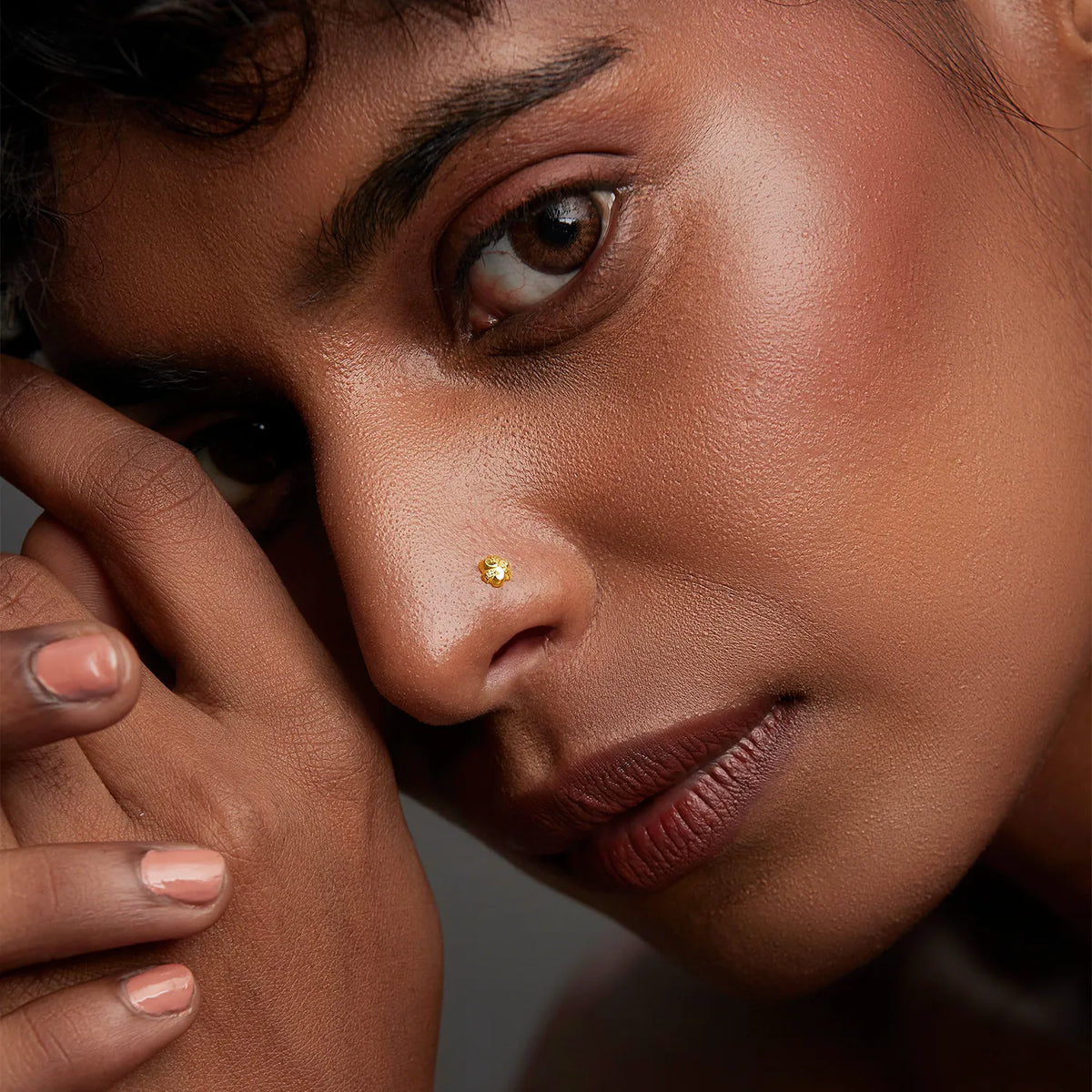 Small round gold nose stud worn on nostril, close-up lifestyle shot