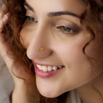 Small round gold nose stud worn on nostril, close-up smiling shot