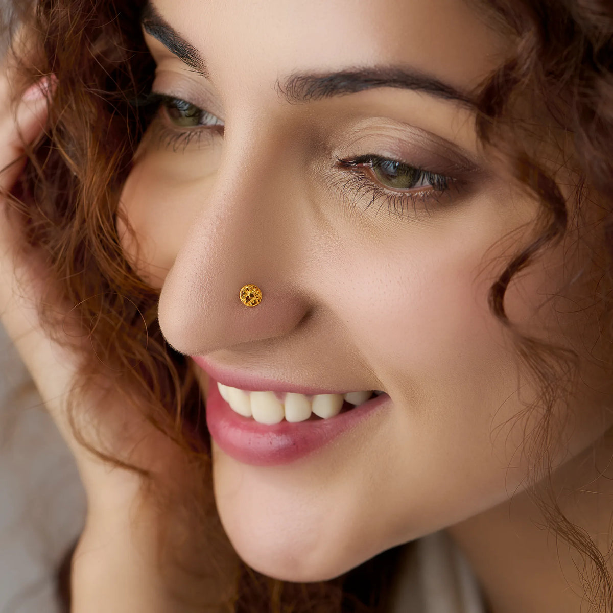 Small round gold nose stud worn on nostril, close-up smiling shot