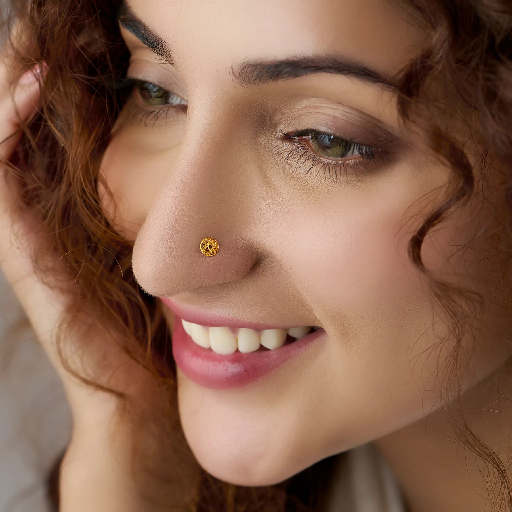 Small round gold nose stud worn on nostril, close-up smiling shot