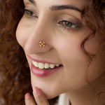 Woman wearing round gold nose pin with pink stone cluster