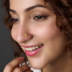 Woman smiling with a round gold nose pin