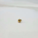 Side view of a round gold nose pin with faceted center and screw-back post