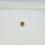 Round gold nose pin with a faceted center and textured border on a white surface