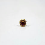 A gold stud earring with a large ruby center stone surrounded by a halo of brown stones, placed on a white background