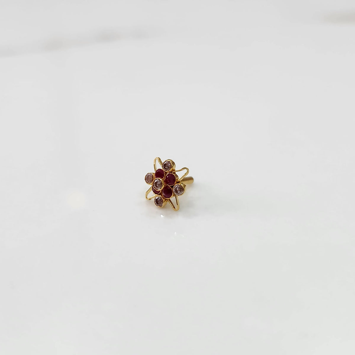 Gold statement ring with ruby red and clear gemstones in floral starburst design