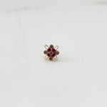 Top view of gold cocktail ring with red ruby and clear stones in flower design