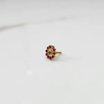 Large gold nose pin with ruby-colored gemstone petals and clear center stone on white background