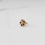 Gold nose pin with ruby-colored gemstone petals and clear center stone on white background