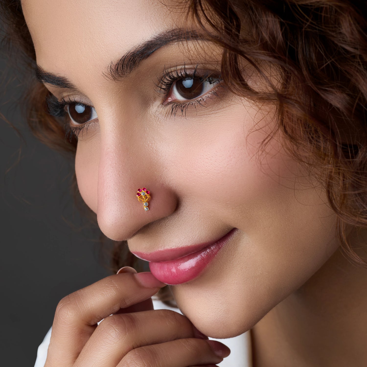 Woman wearing a gold nose pin with ruby stone accent
