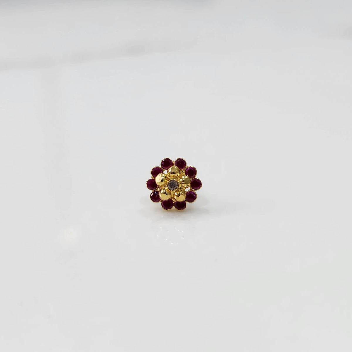 Front view of gold floral ring with ruby-red stone petals