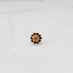 Front view of gold floral ring with ruby-red stone petals