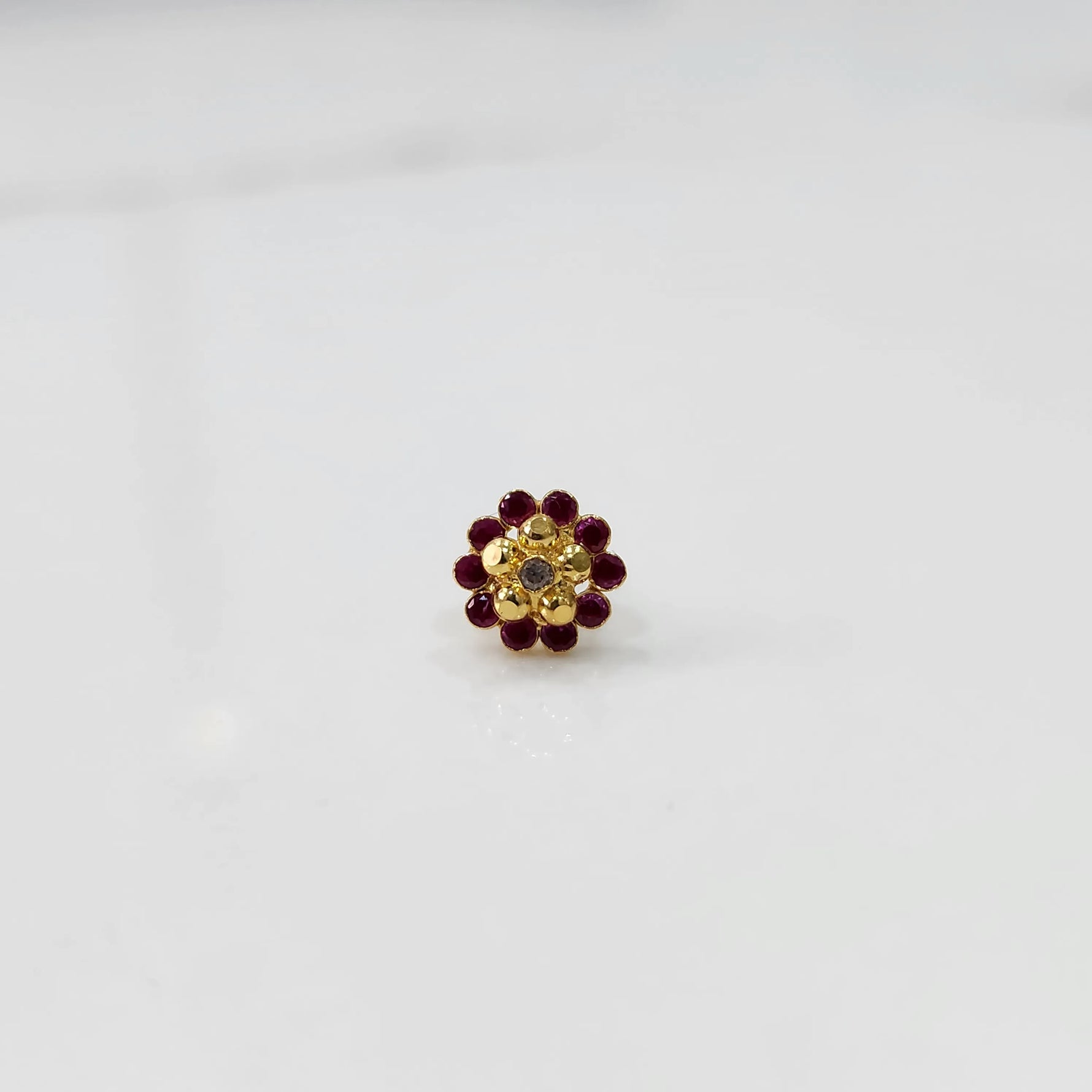 Front view of gold floral ring with ruby-red stone petals