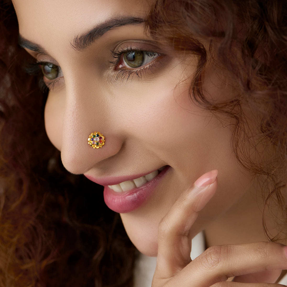 Woman wearing gold ruffled flower nose pin with pink stones