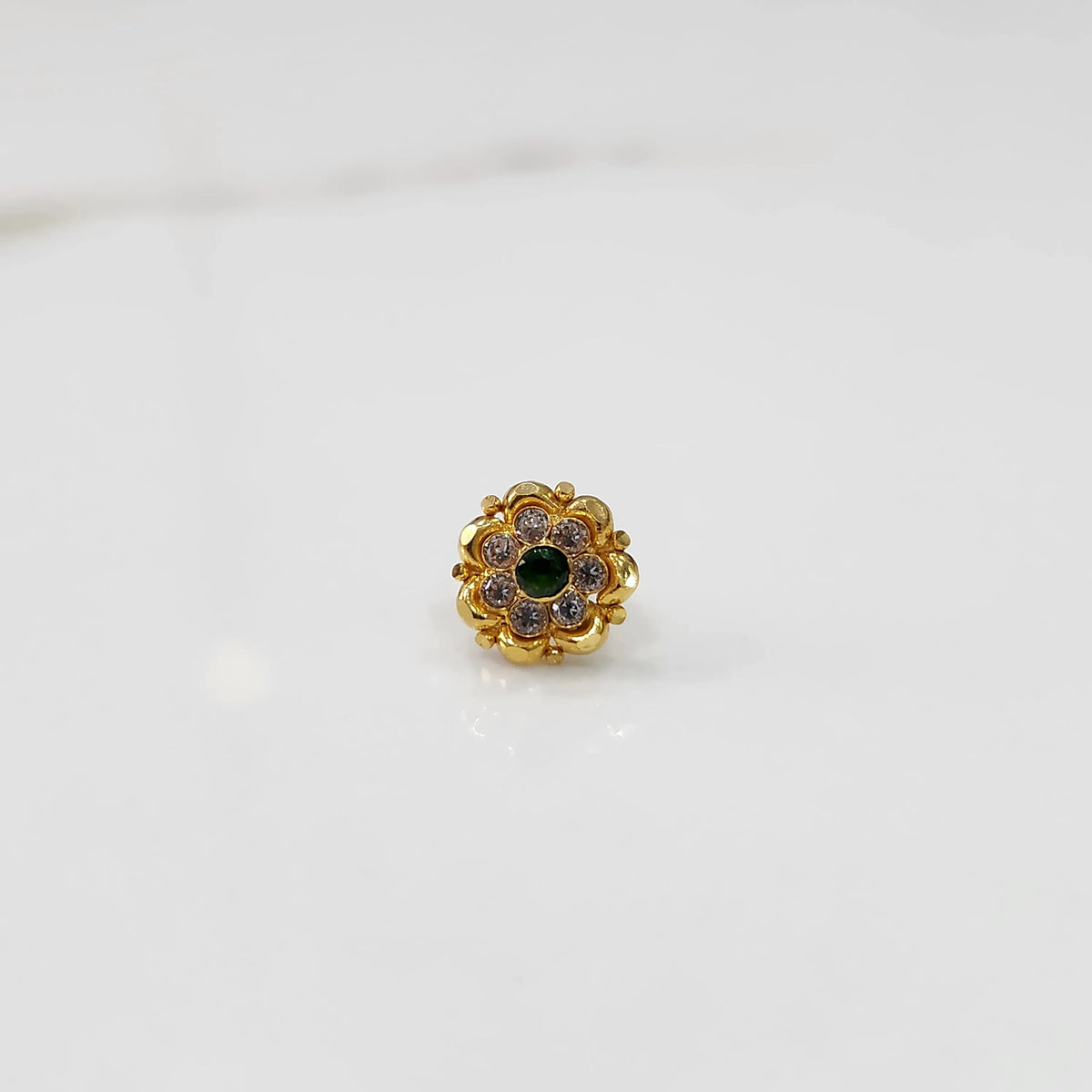 Top view of gold floral ring with green center stone