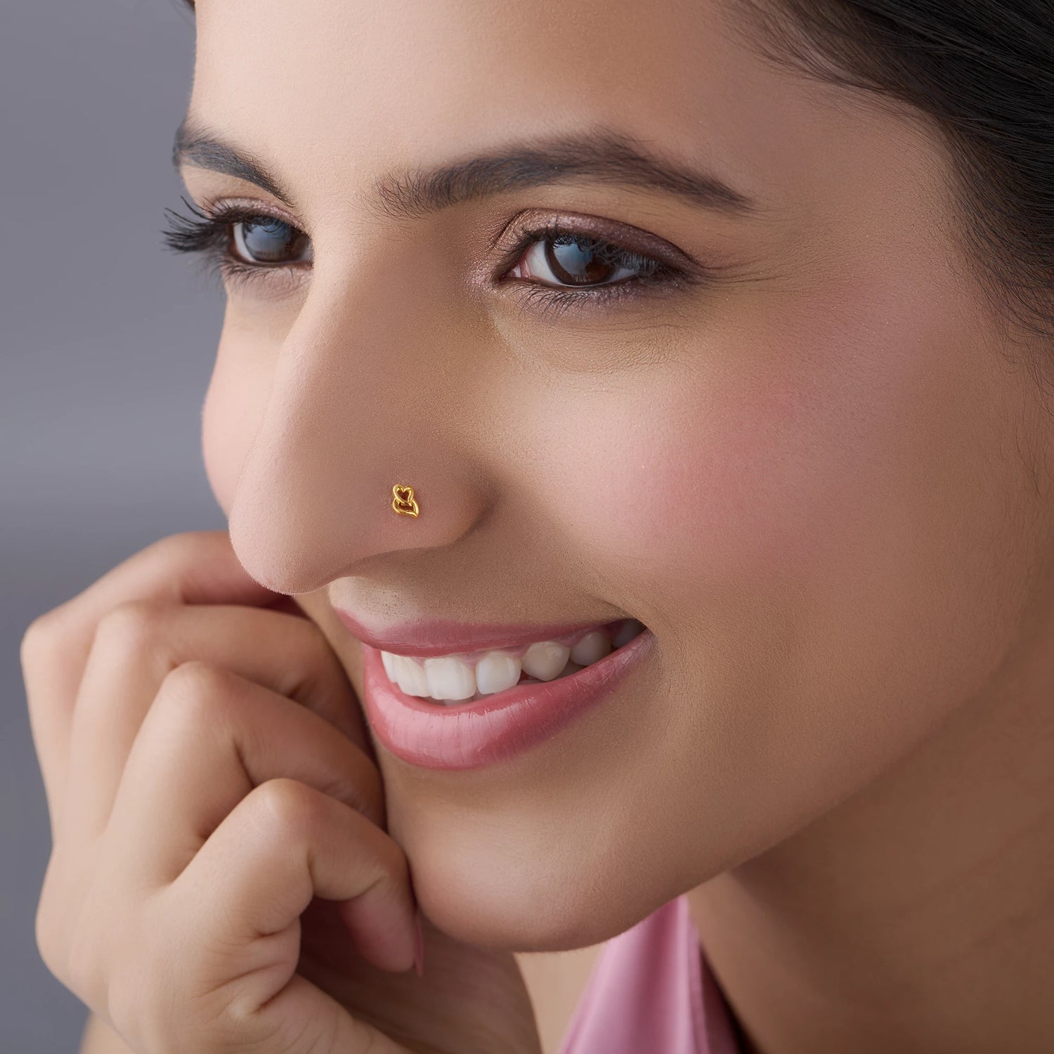Close-up of woman wearing scalloped gold nose pin, smiling