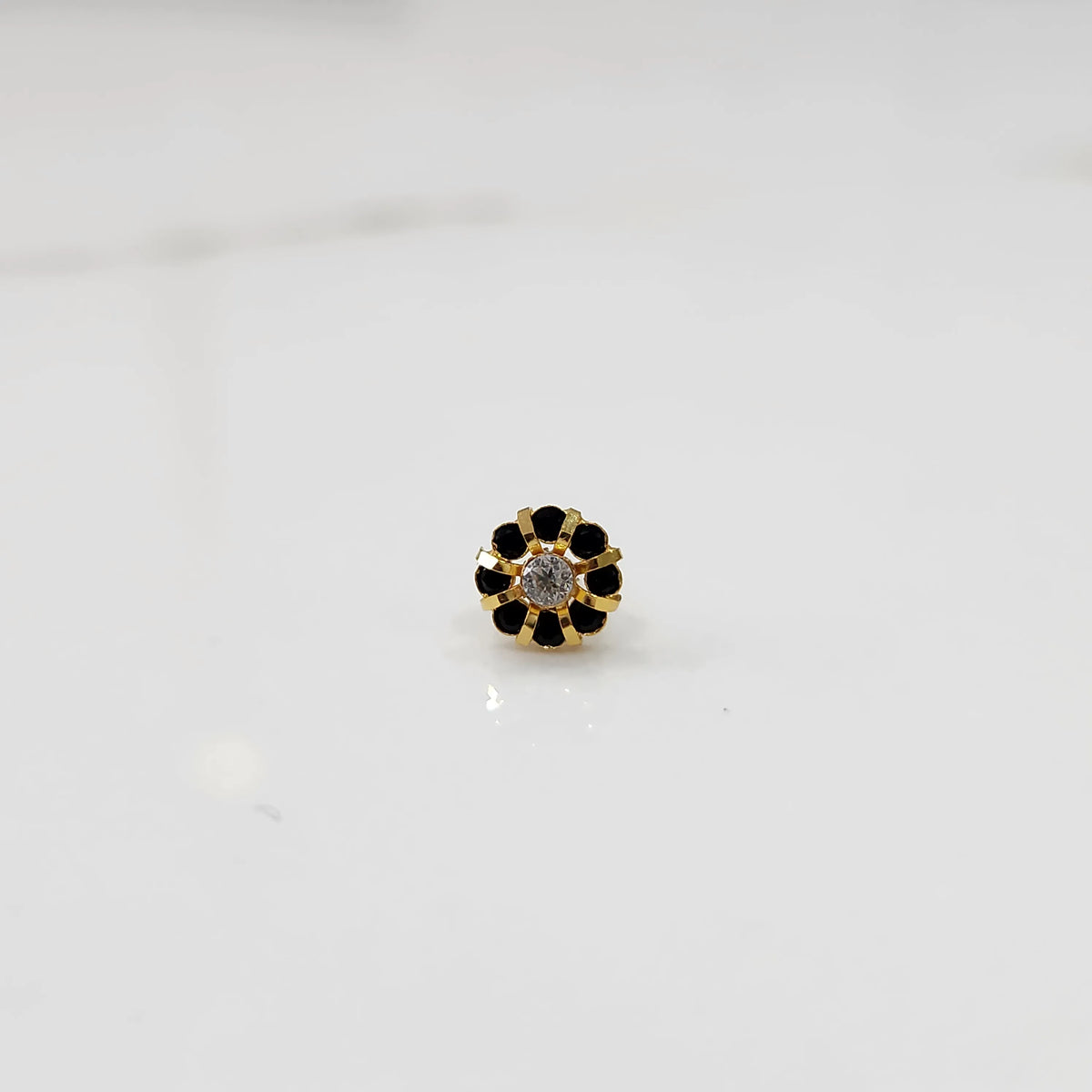 Top view of gold ring with clear center stone and black petal stones