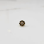 Top view of gold ring with clear center stone and black petal stones