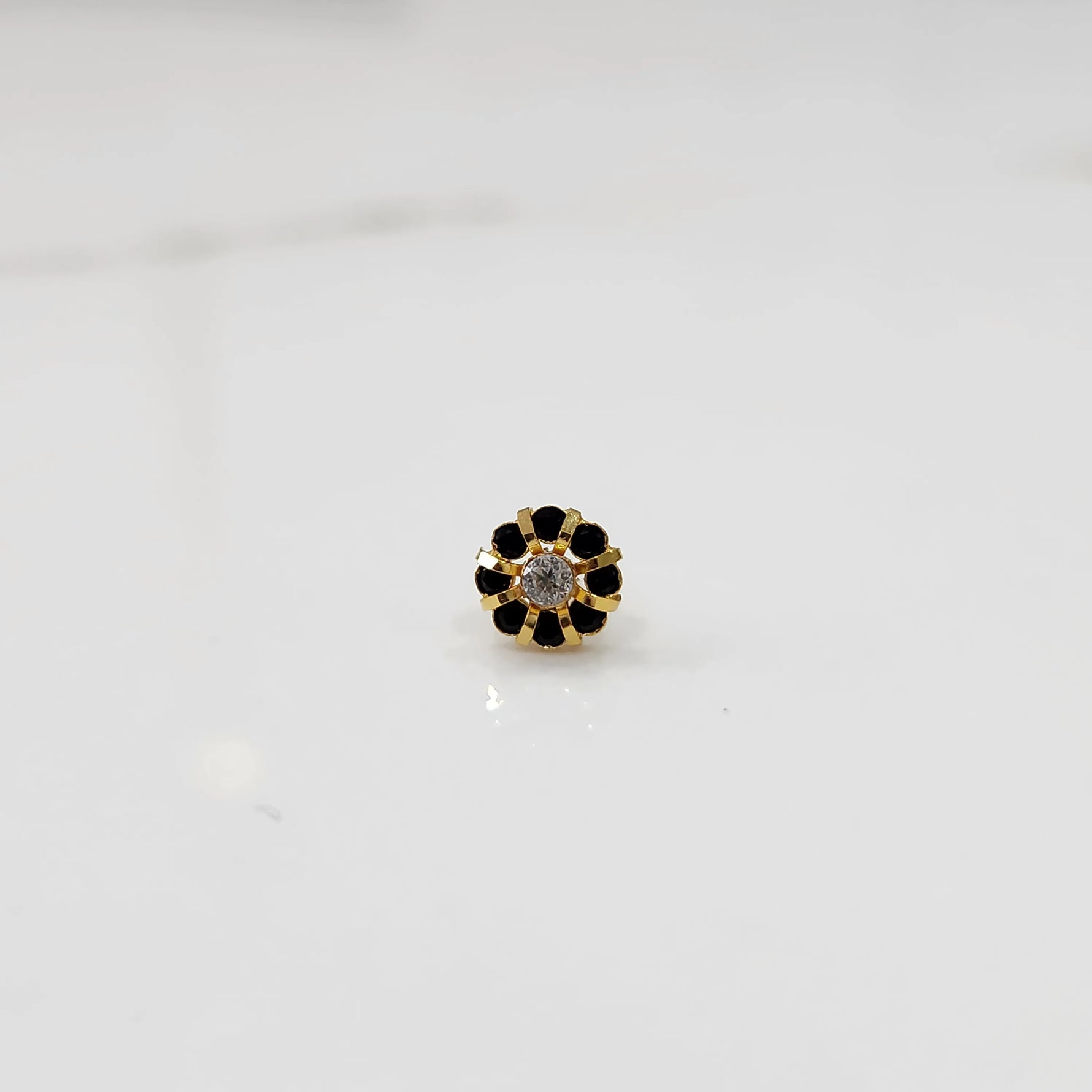 Top view of gold ring with clear center stone and black petal stones