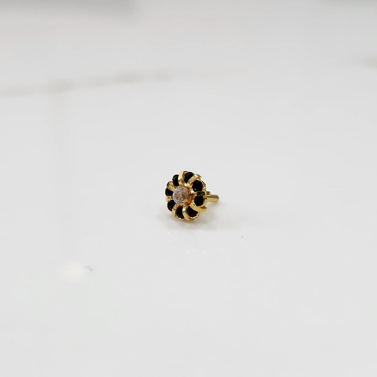 Gold ring with sculpted petal design and clear center with black stones