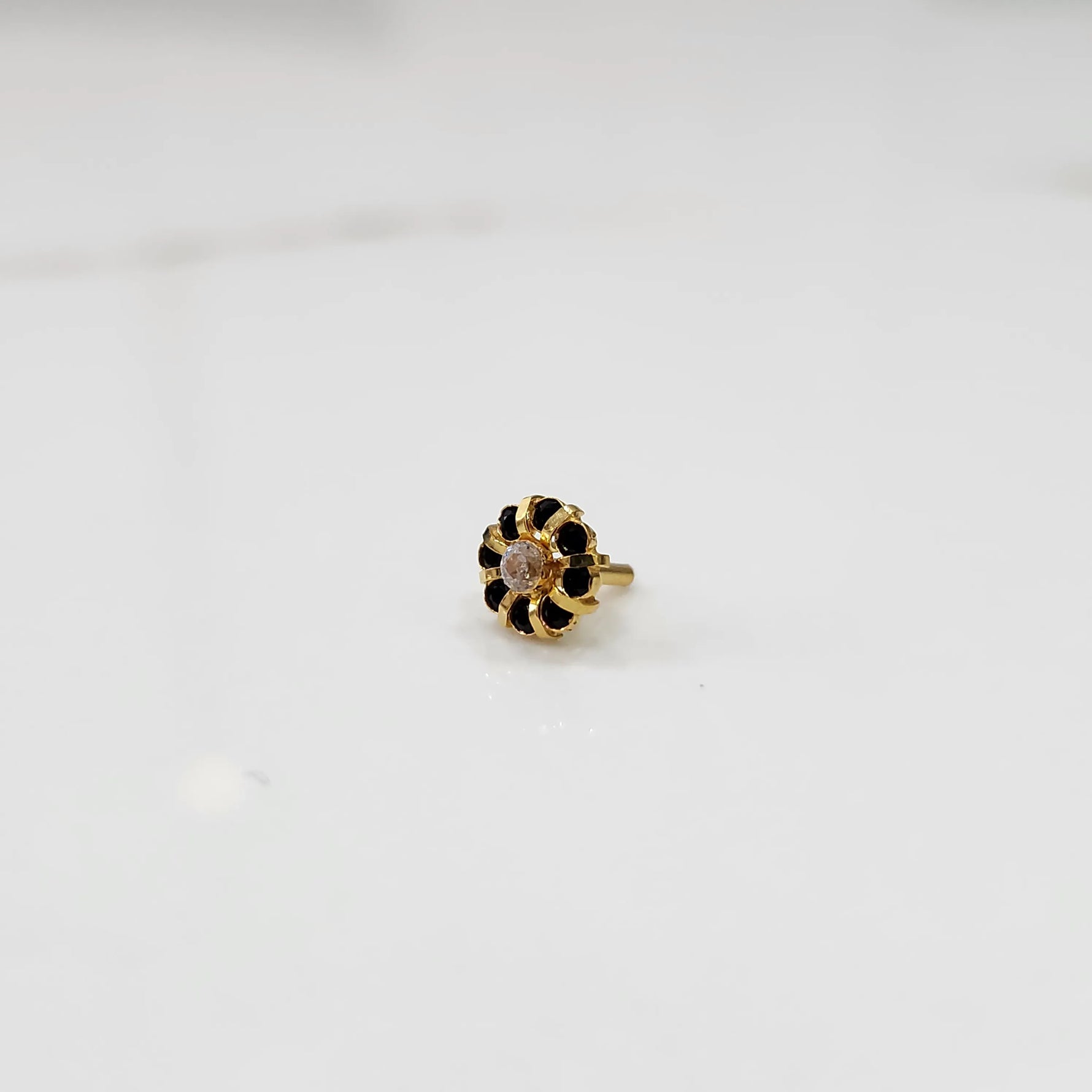 Gold ring with sculpted petal design and clear center with black stones