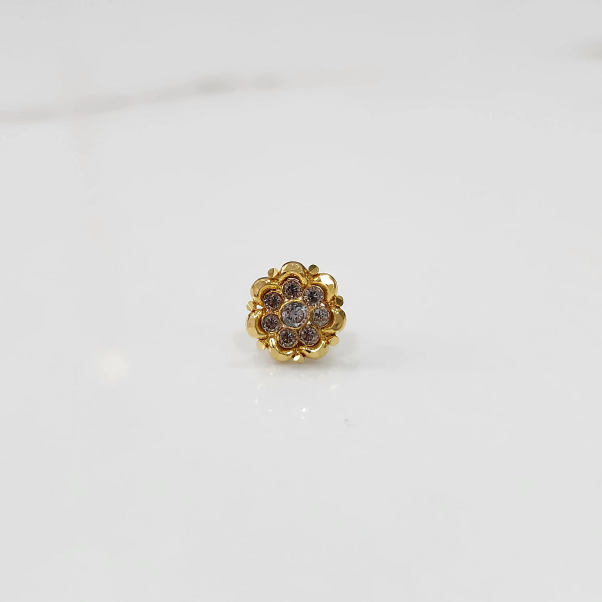 Close-up of gold ring featuring rounded petals with pink gemstones